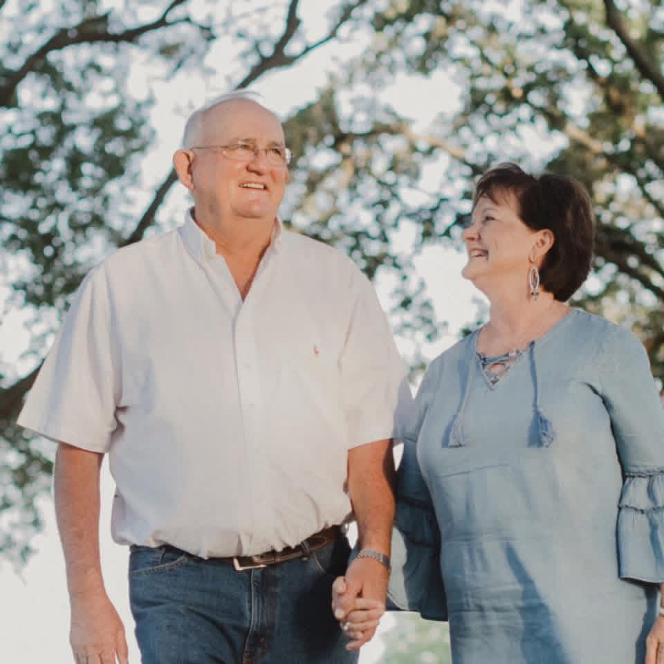 Older couple holding hands outdoors, smiling at each other — vow renewal